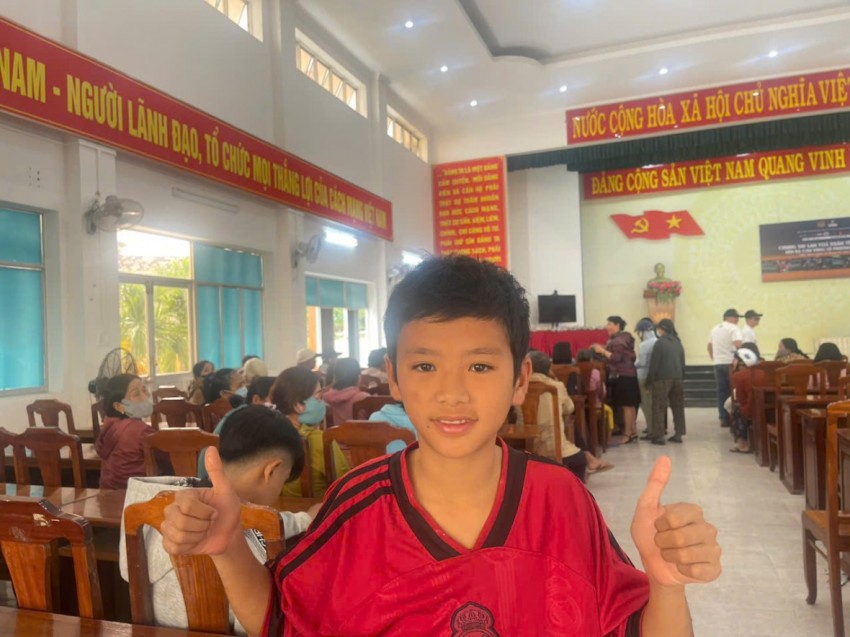 Bé Phong (học sinh lớp 7, Trường THCS Nguyễn Thị Định) không giấu được niềm vui khi được đến nhận phần quà Tết từ chương trình. Nụ cười rạng rỡ và cái giơ tay đầy hào hứng của em như gửi gắm mong ước về một mùa xuân ấm áp, đủ đầy hơn sau những ngày gia đình chịu ảnh hưởng bởi mưa lũ.