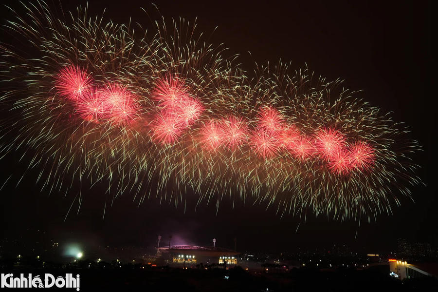 High-altitude fireworks are positioned along Le Duc Tho Street, extending the display beyond the stadium grounds.