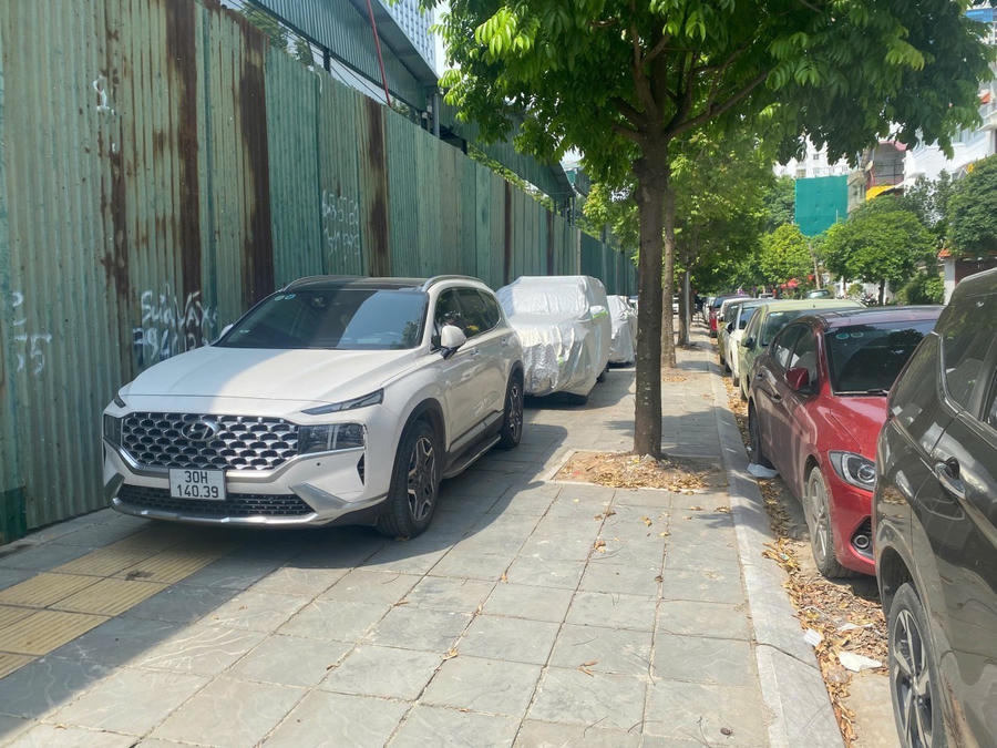 Xe ô tô đỗ hàng dài trên vỉa hè chỉ để lại một lối đi nhỏ cho người đi bộ trên đường Hoàng Quán Chi, phường Cầu Giấy.