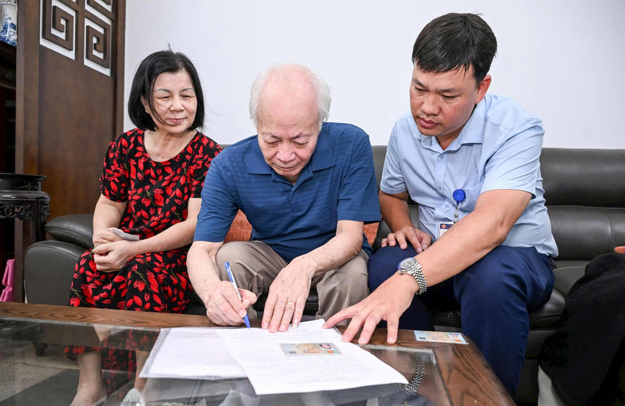 Anh Lê Minh Thiện, cán bộ Điểm hỗ trợ DVC số Phương Liệt đến nhà hỗ trợ ông Nguyễn Xuân Bình làm thủ tục ủy quyền nhận lương hưu. Ảnh: N.Đạt
